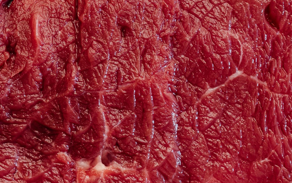 Primer plano de carne de ternera cruda, el componente principal de la dieta BARF